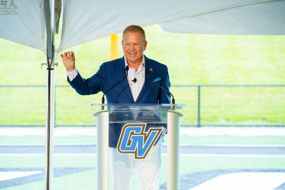 Brian Kelly speaking, holding up a fist at the Jamie Hosford Football Center dedication.
